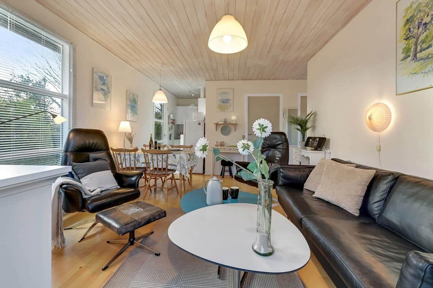 Living and dining area with leather sofa, chair, and wooden table.