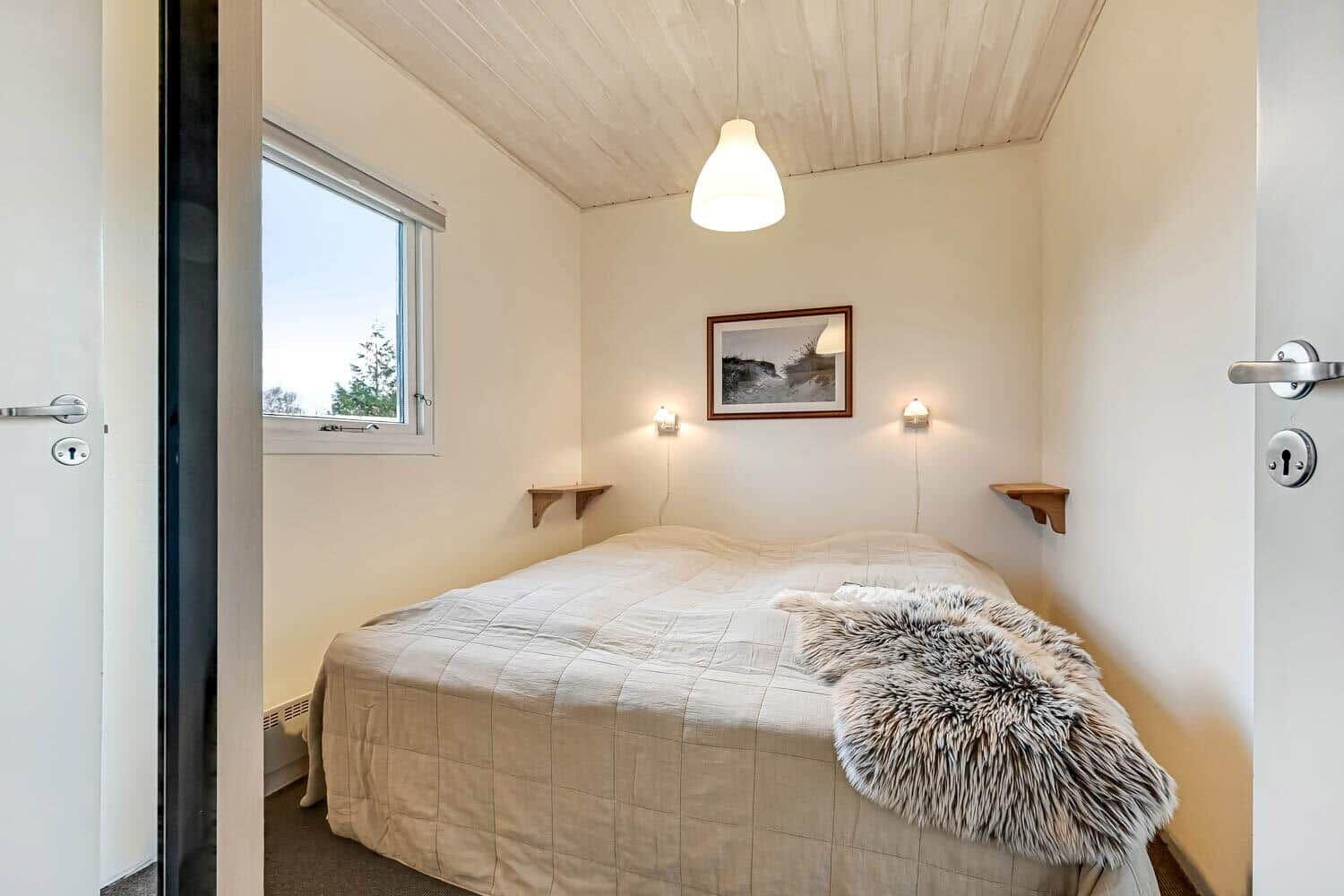 Bedroom with bed, window, and ceiling light.