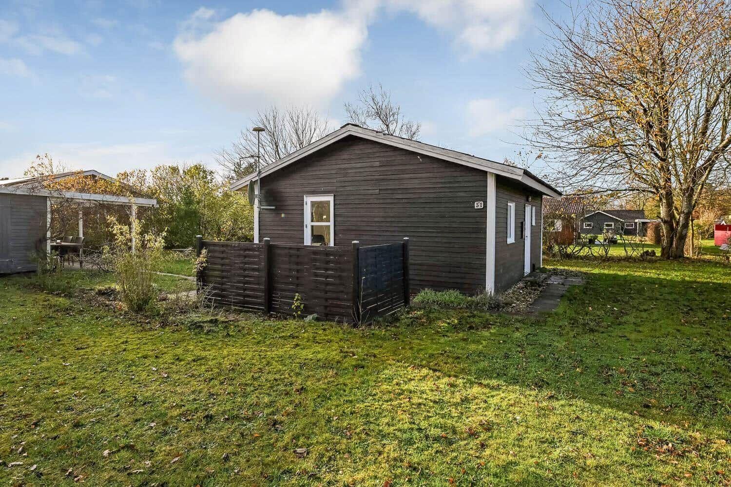 A small house with wooden siding and garden. Number 51 is displayed.
