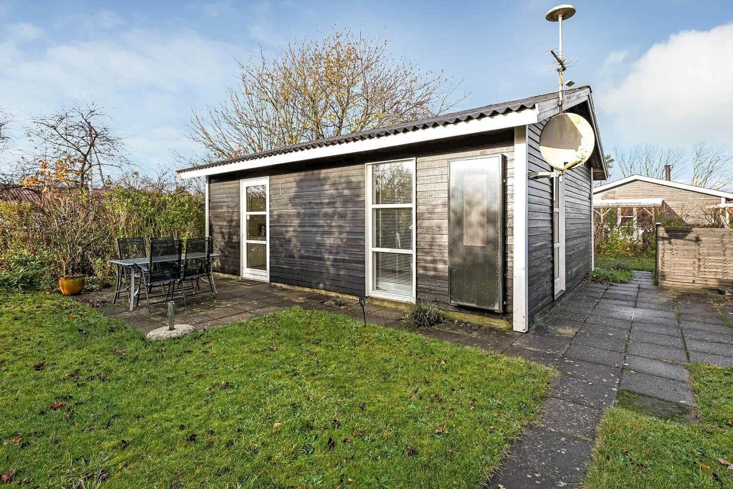 A small house with garden, table and chairs, and satellite dish.
