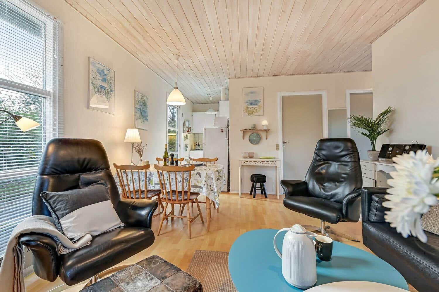 Living area with dining space, two black leather chairs, and hardwood floor.