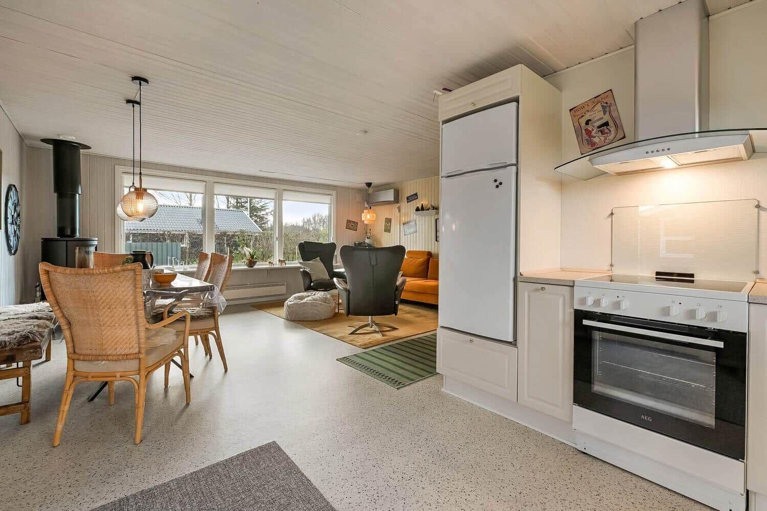 Kitchen with fridge and stove. Dining area with table and chairs. Living area with seating.
