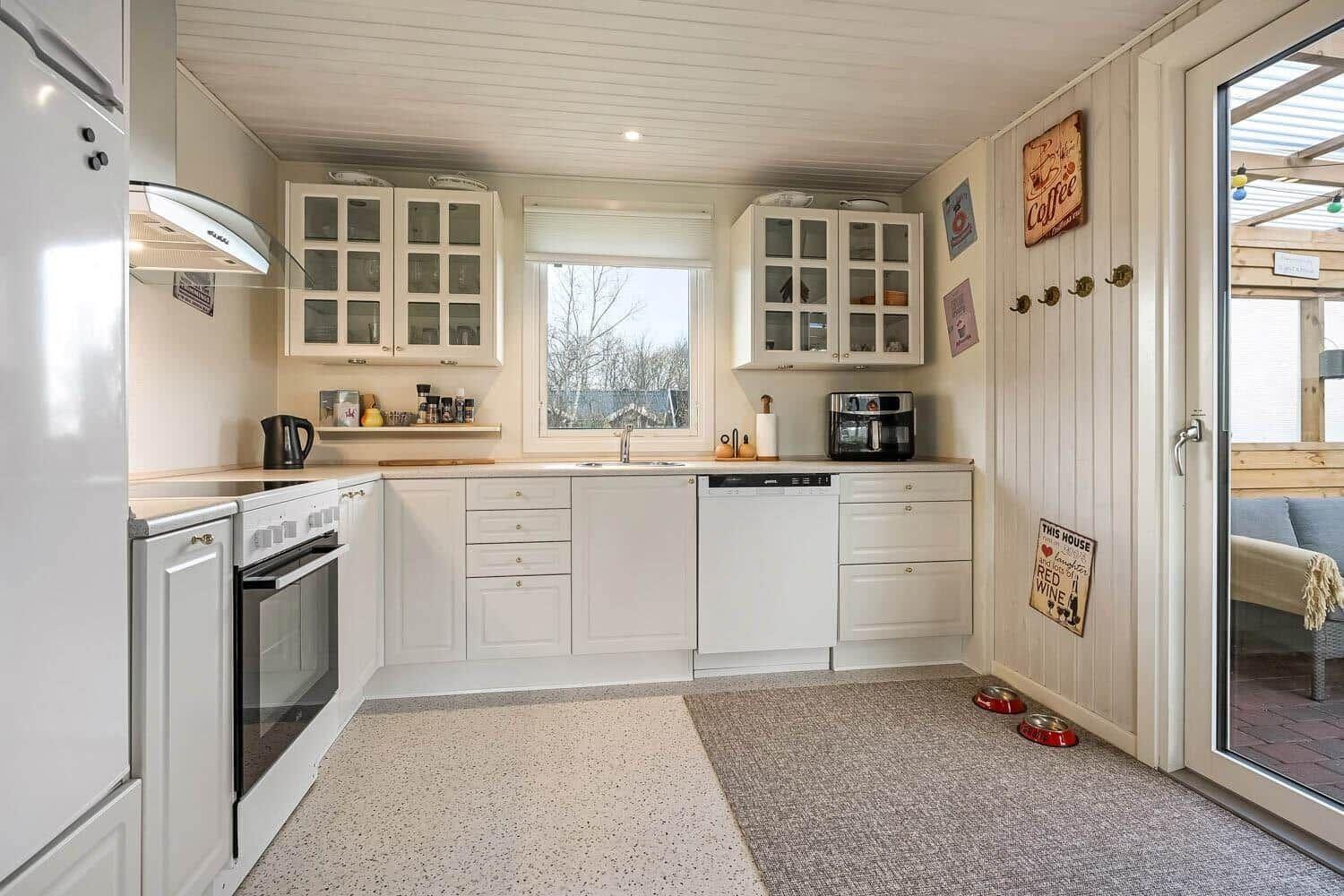 Kitchen with white cabinets, window, and door to outdoor area.