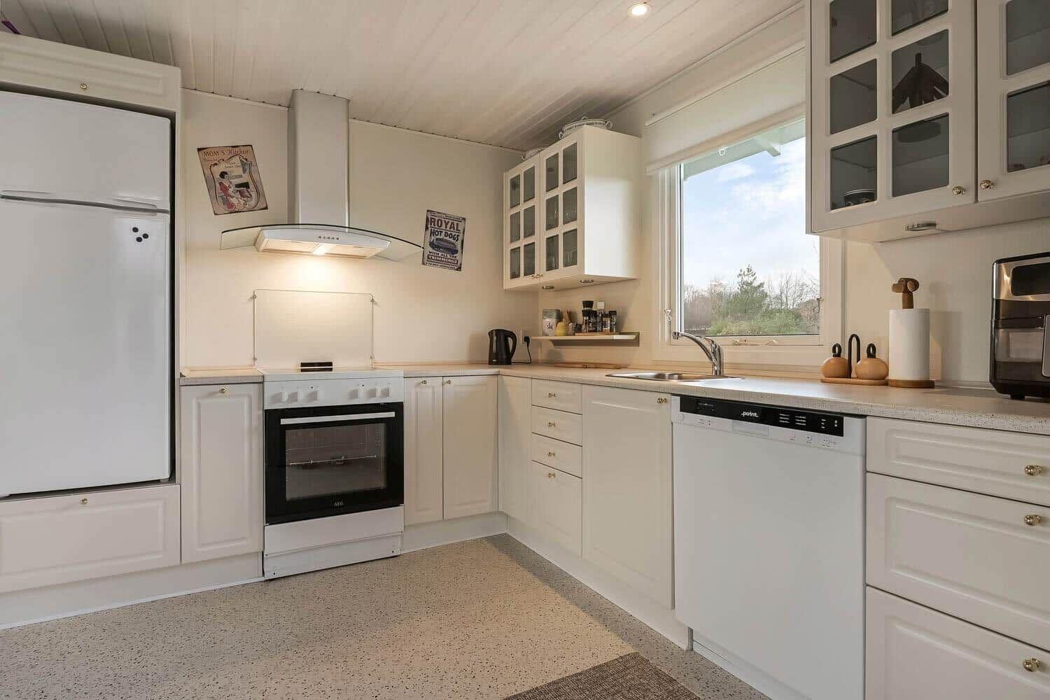 Kitchen with white cabinets, sink, refrigerator, and window.