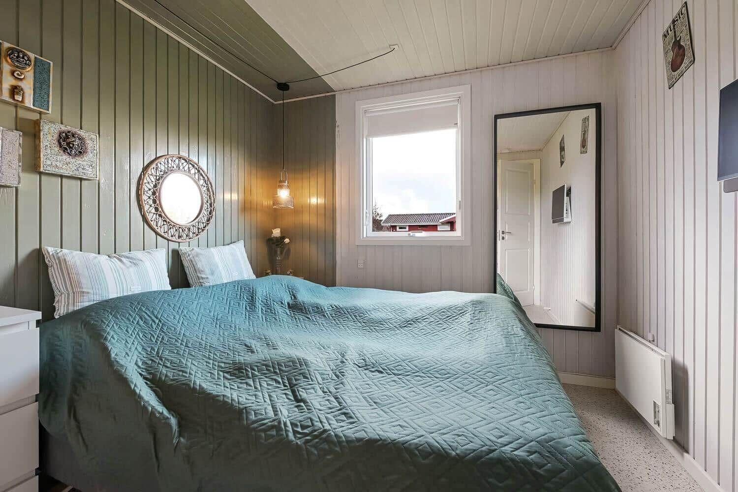 Bedroom with bed, window, and mirror on the wall.