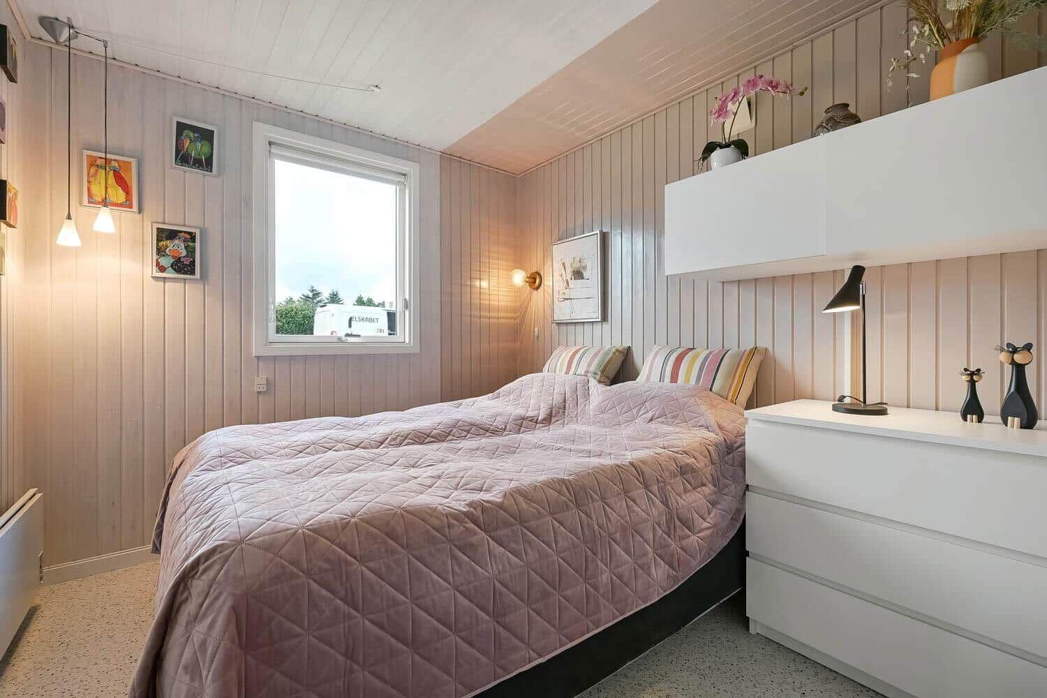 Bedroom with bed, dresser and window. Walls are panelled.