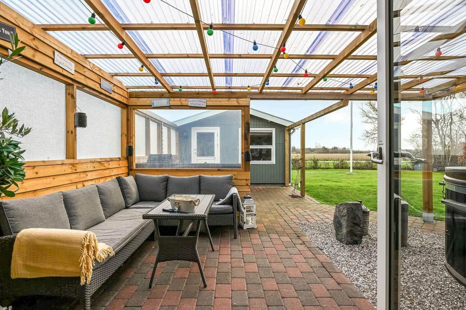 Terrace with seating, string lights, and view of garden and house.