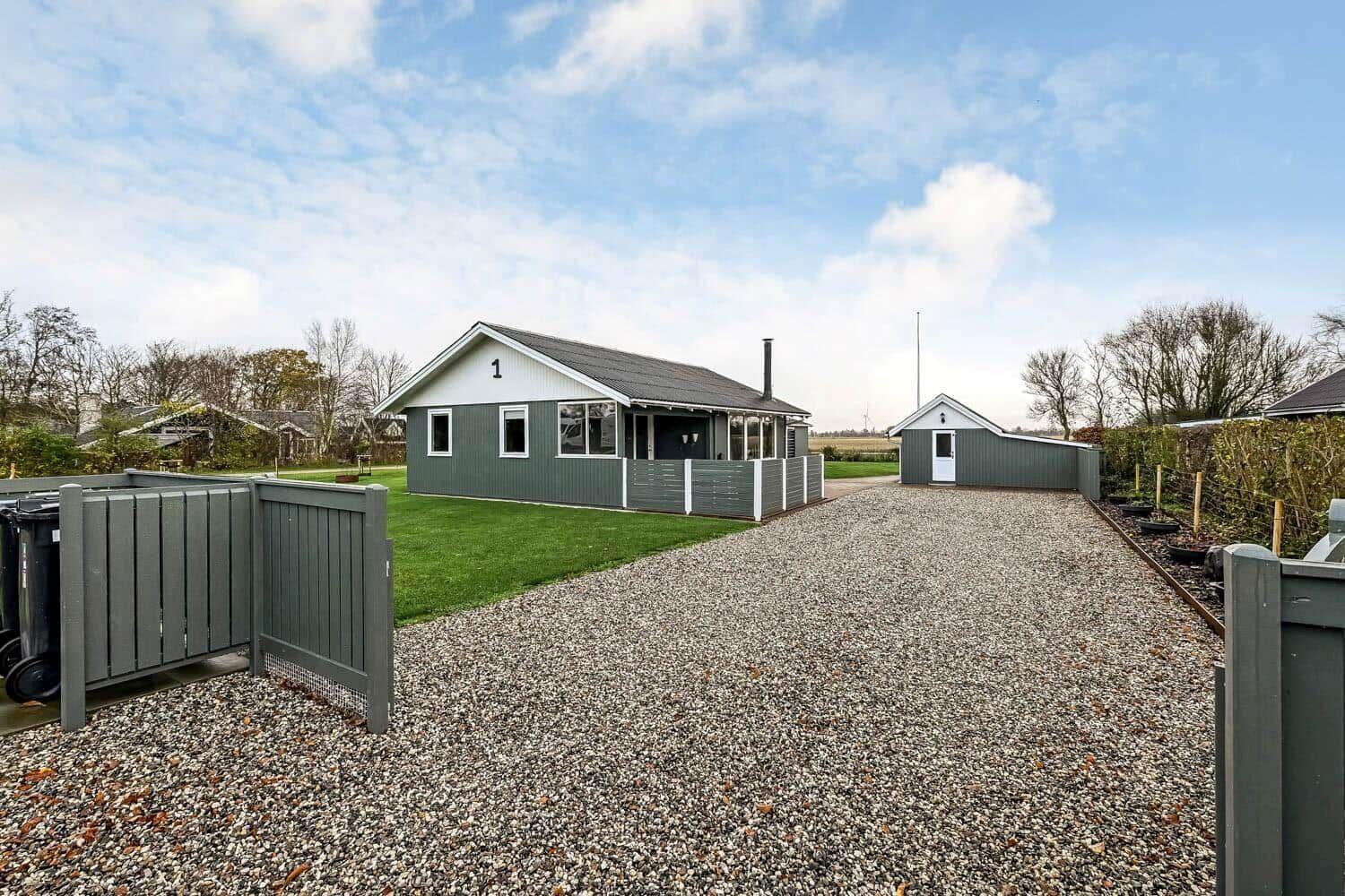 Modern holiday home with gravel path and green lawn area.