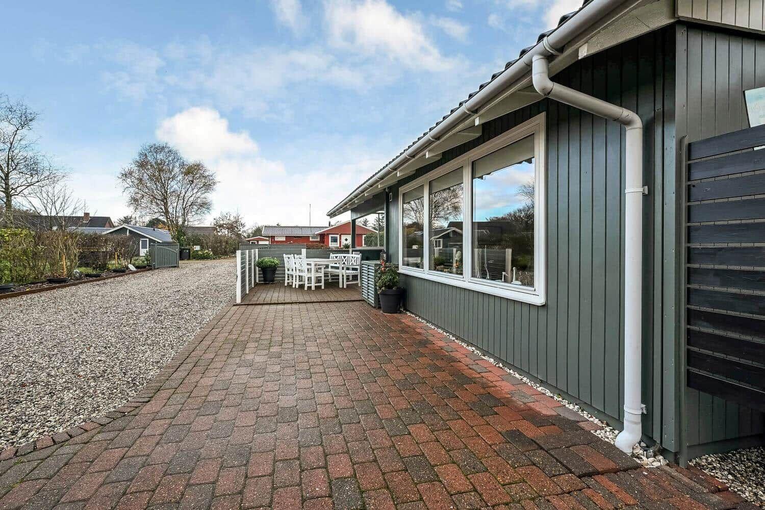 House with terrace, table and chairs, paved path and grass area