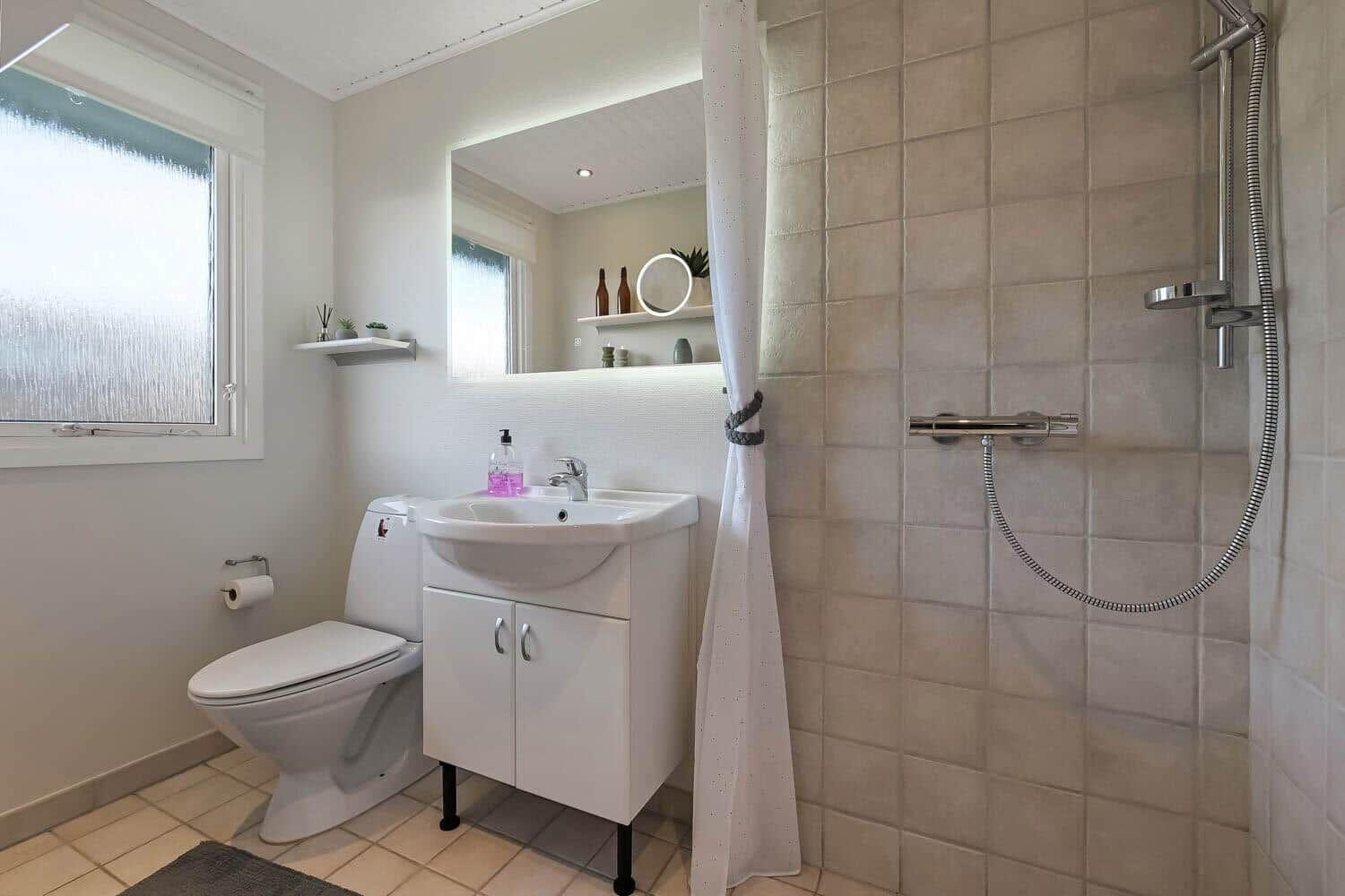 Bathroom with shower, sink and toilet. Window with frosted glass.