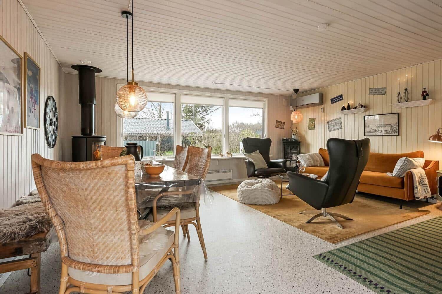 Living and dining area with seating and wood paneling.