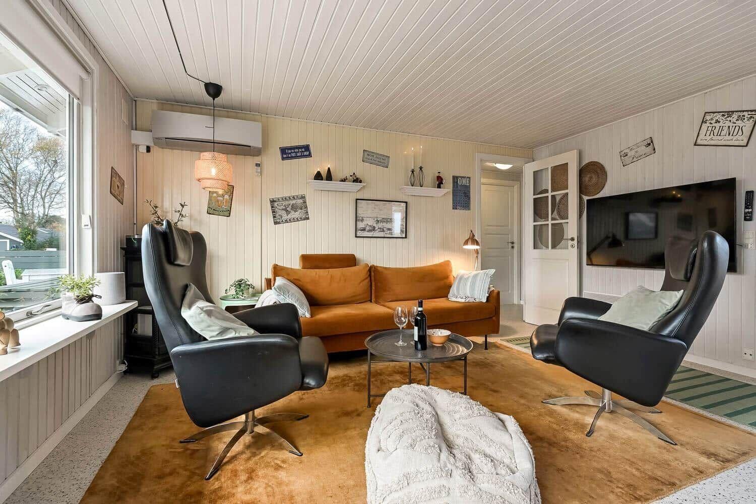 Living room with sofa, two chairs, and TV mounted on the wall.
