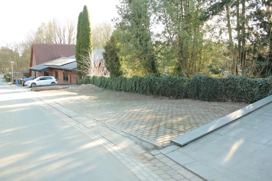 Pflasterter Hof mit Hecke und Wohnhaus im Hintergrund.