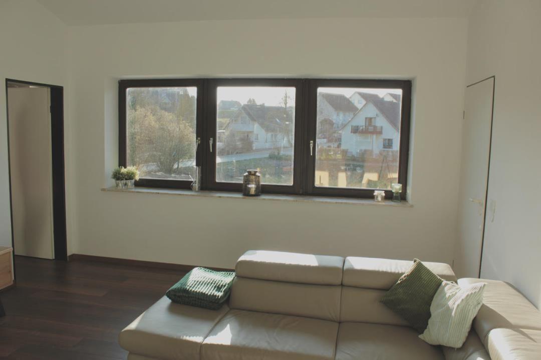 Wohnzimmer mit Sofa, Fenster und Blick auf die Straße