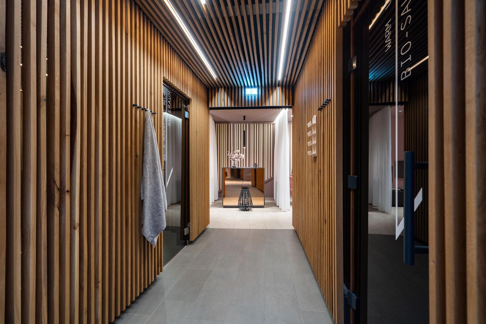 Flur mit Holzwänden, Tür zu Bio-Sauna und Ruheraum, modern eingerichtet.