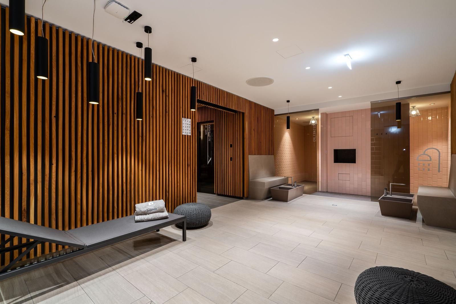 Moderne Wellnessbereich mit Holzwand, Duschen und Liegeflächen.