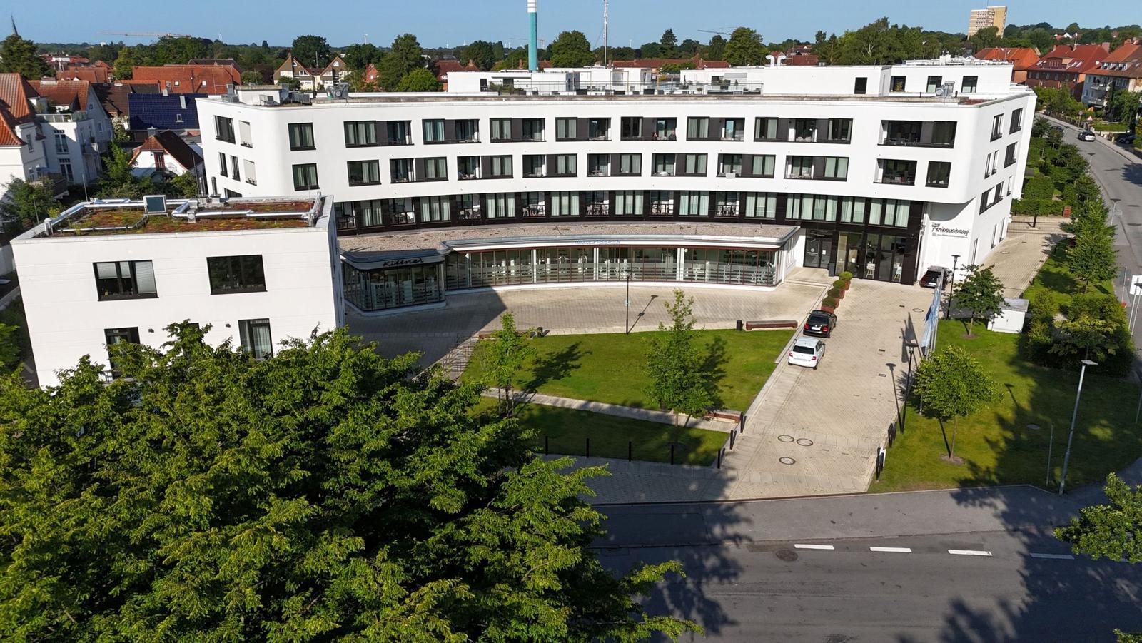 Modernes Gebäude mit Terrasse und Grünfläche im Vordergrund.