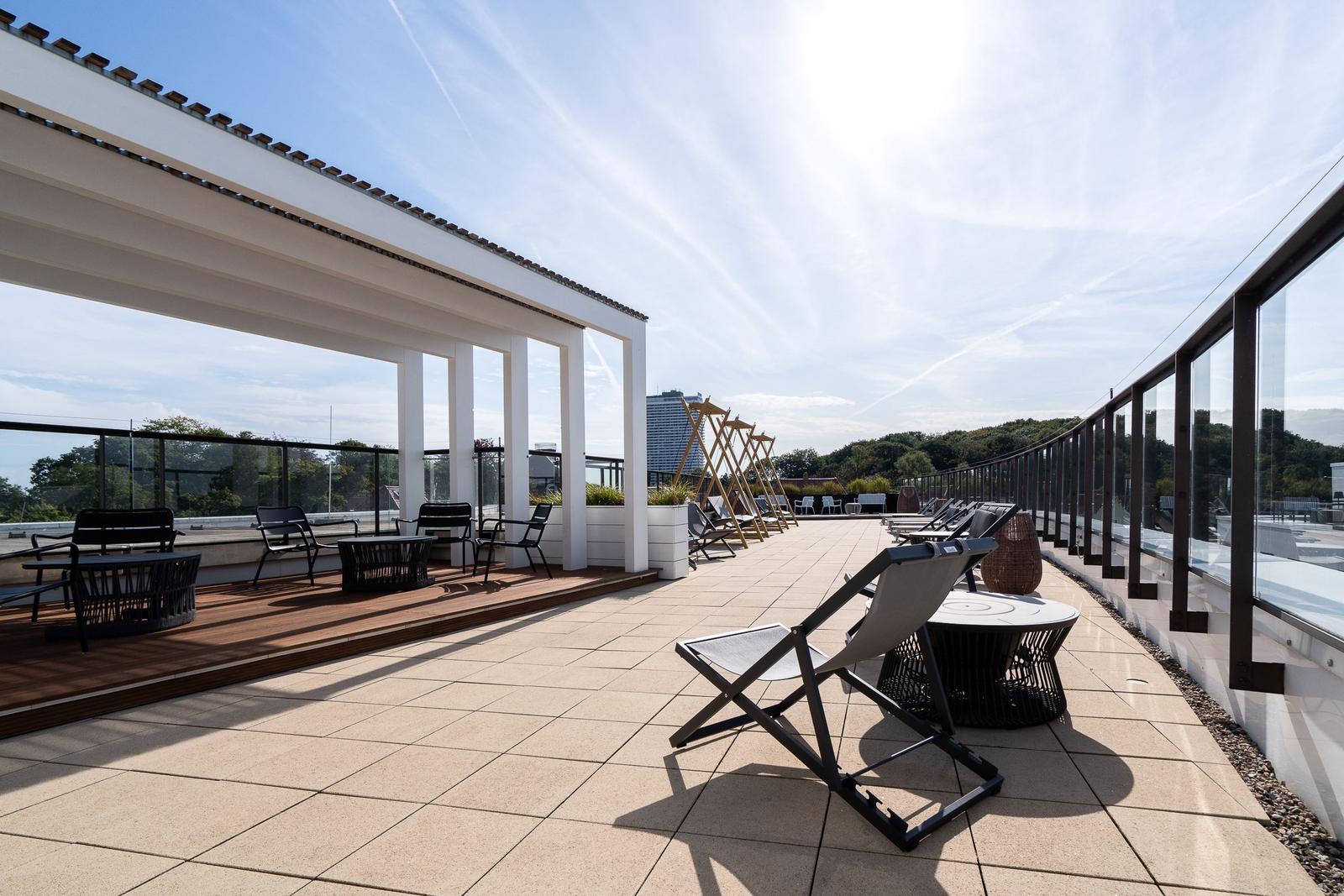 Terrasse mit Liegestühlen und Sitzgelegenheiten unter freiem Himmel.