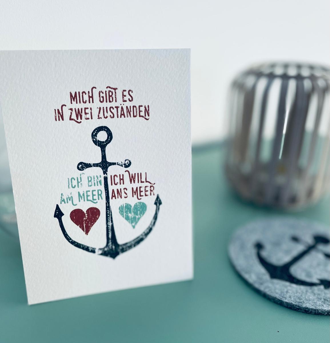 Karte mit Ankermotiv und Text über Meer. Hintergrund mit Glasobjekt.