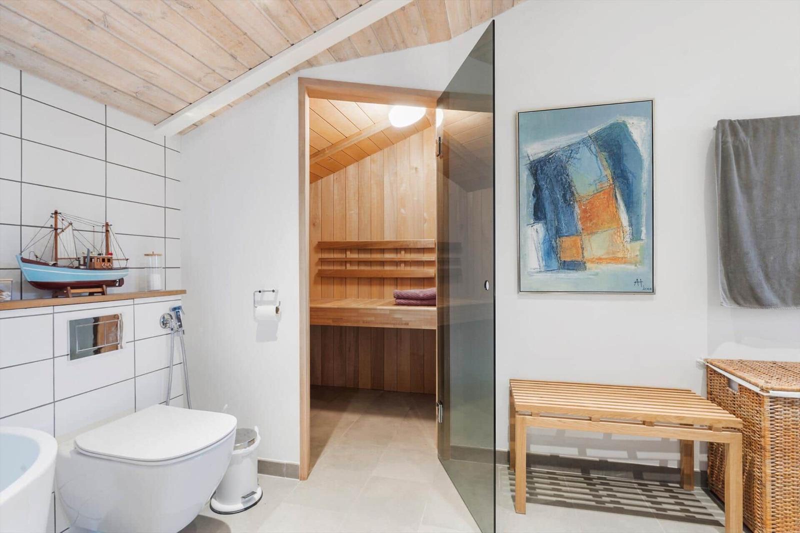 Bathroom with sauna, shower, and wooden floor. A painting hangs on the wall.