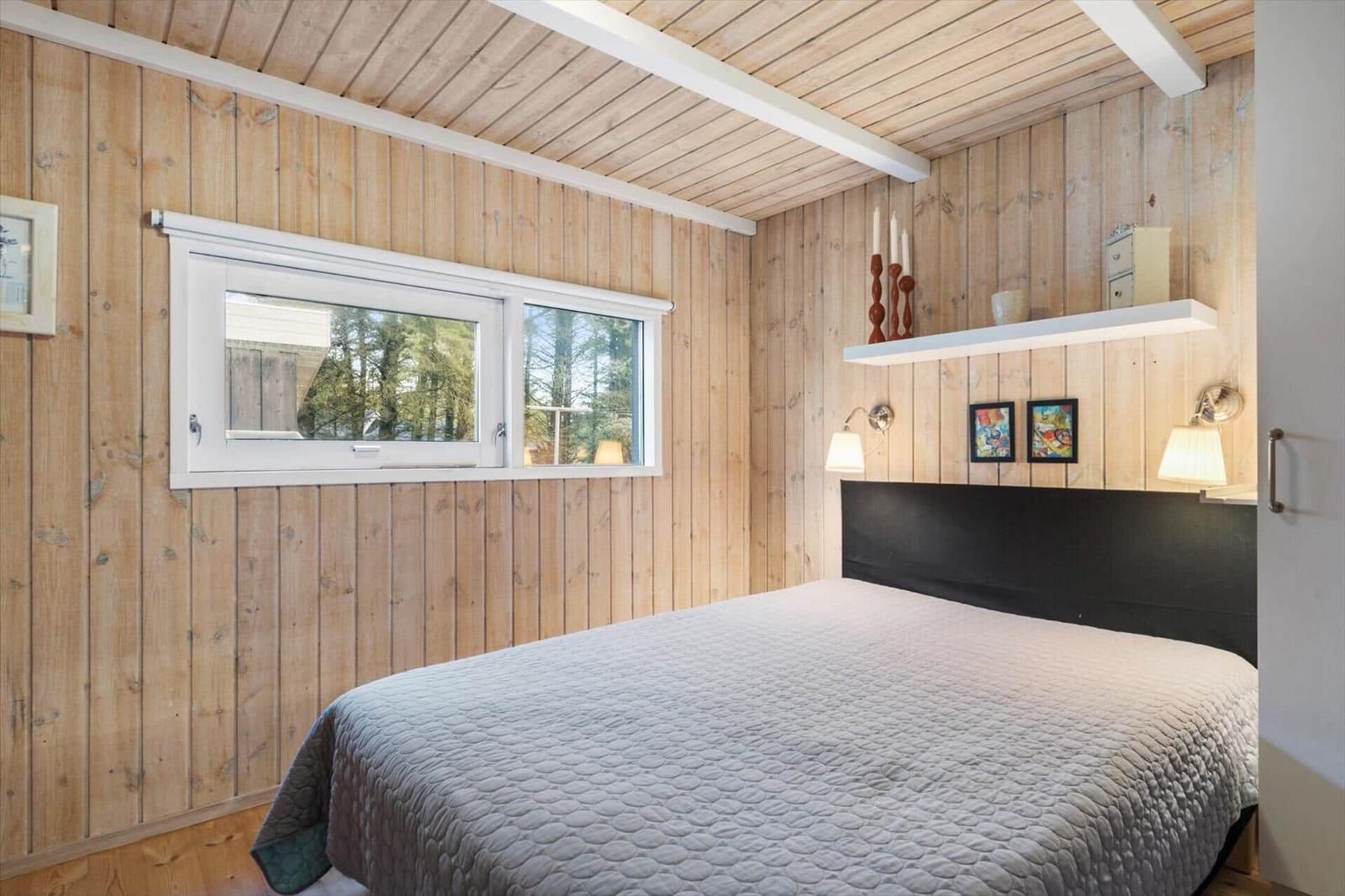 Bedroom with wooden walls, bed, and window.
