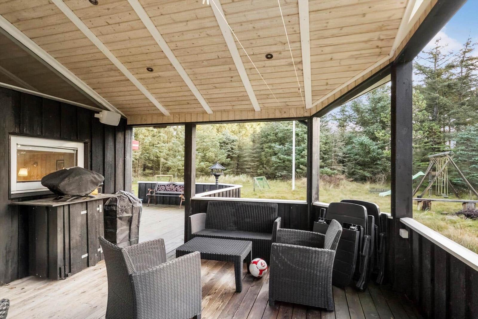 Deck with seating, grill, and view of forest.