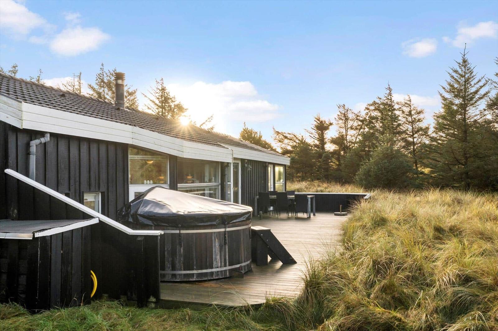 House with outdoor terrace, hot tub, and seating area in the woods