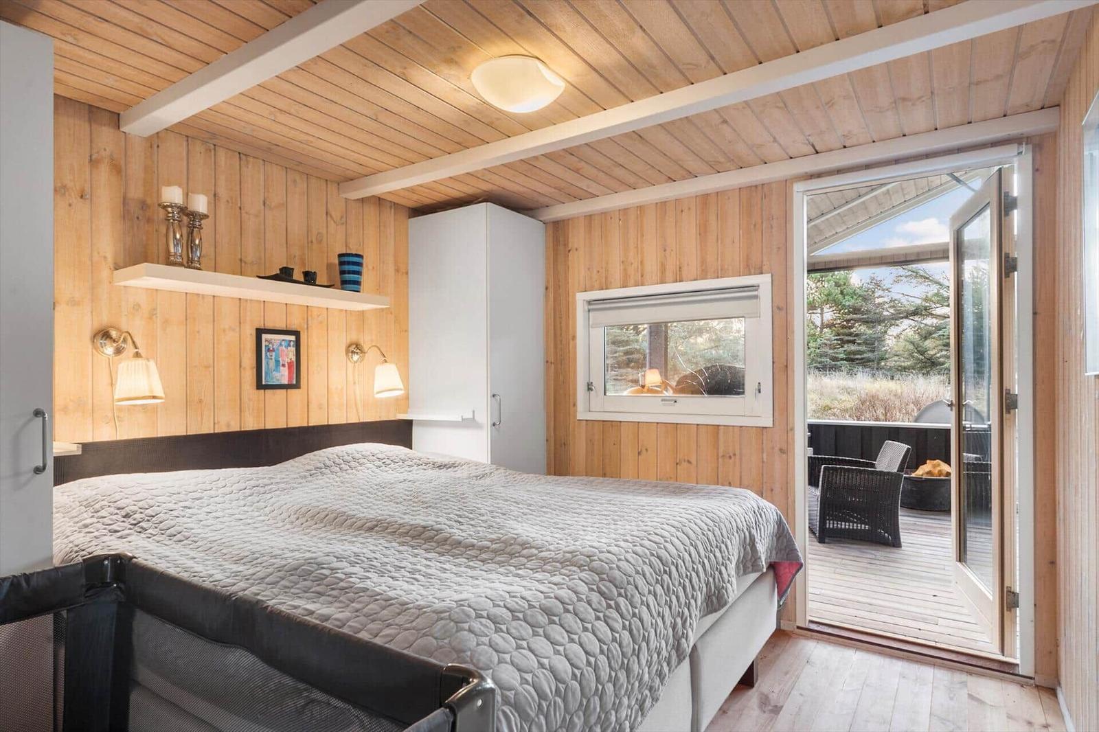 Bedroom with wooden walls and balcony access