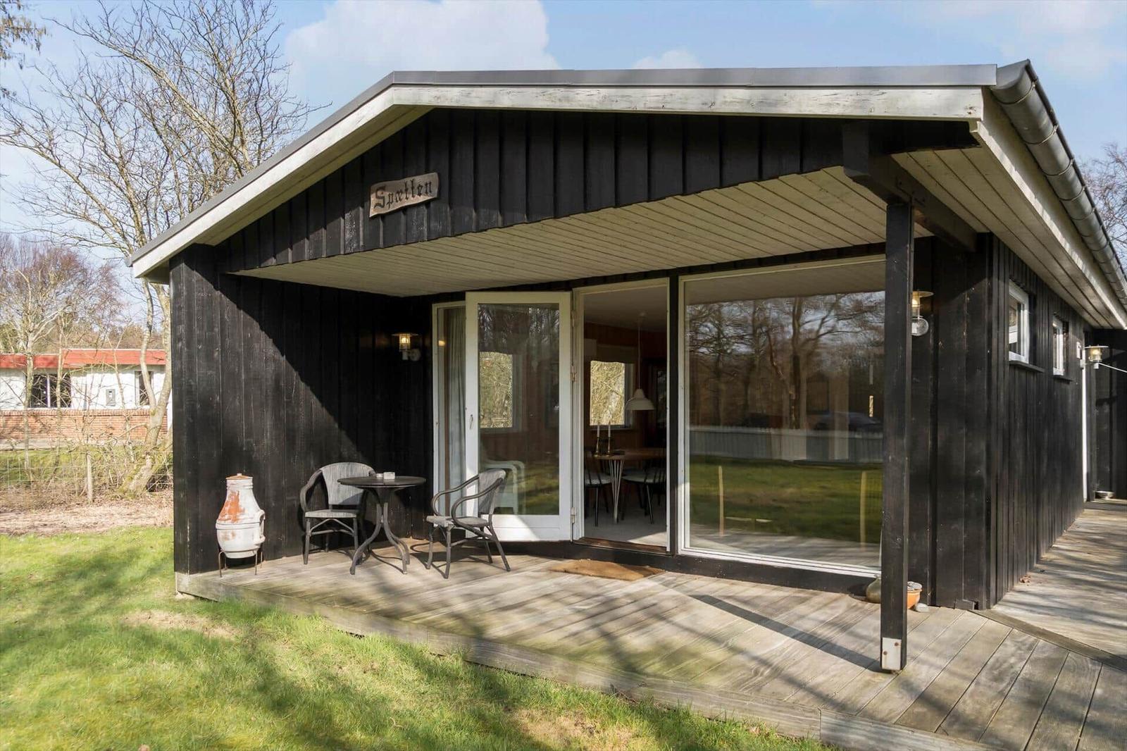 Wooden cabin with terrace, seating area, and garden table. Entrance to interior.