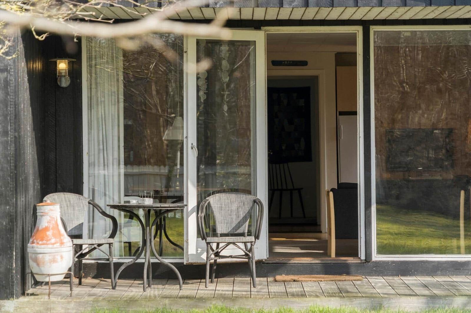 Terrace with table and two chairs in front of a glass door.