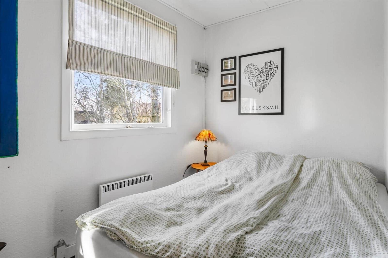Bedroom with bed, window, and wall decor.