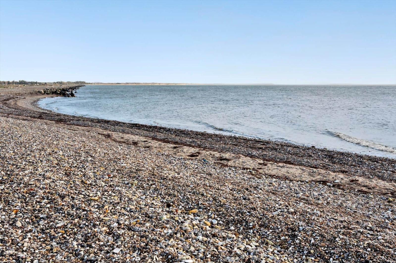Rocky shore with calm water and clear sky view.