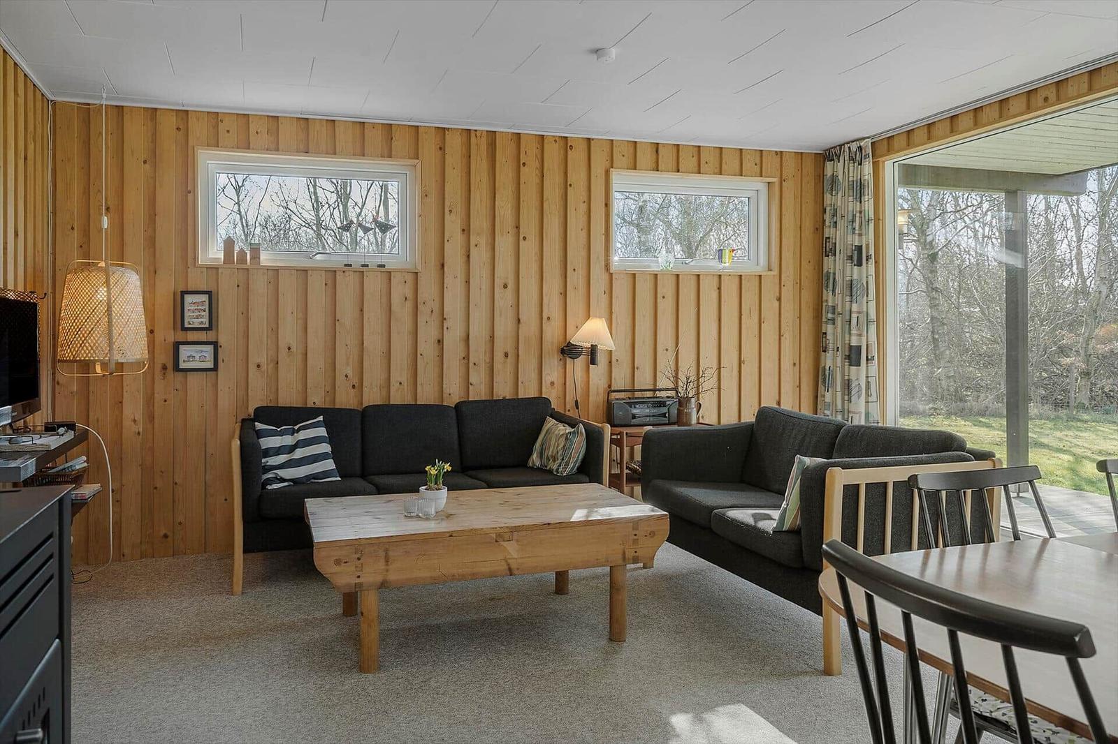 Living room with two sofas, wooden table, and large window to terrace.
