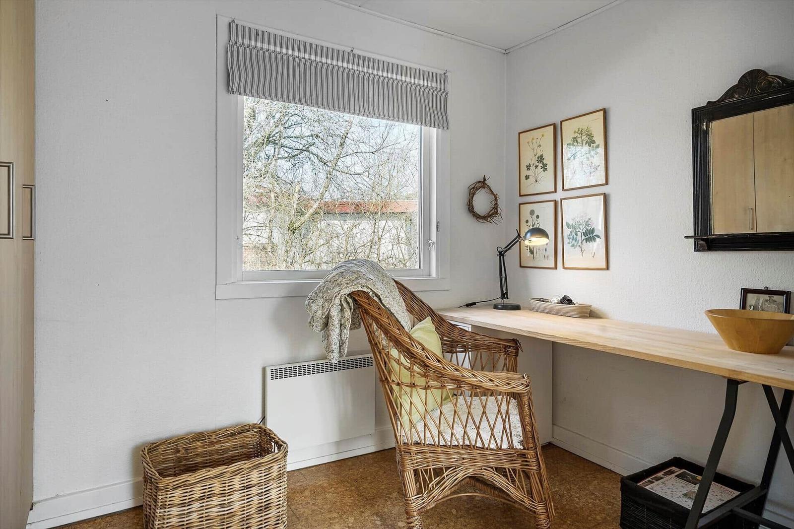 A workspace with desk, chair, and window. Four pictures hang on the wall.