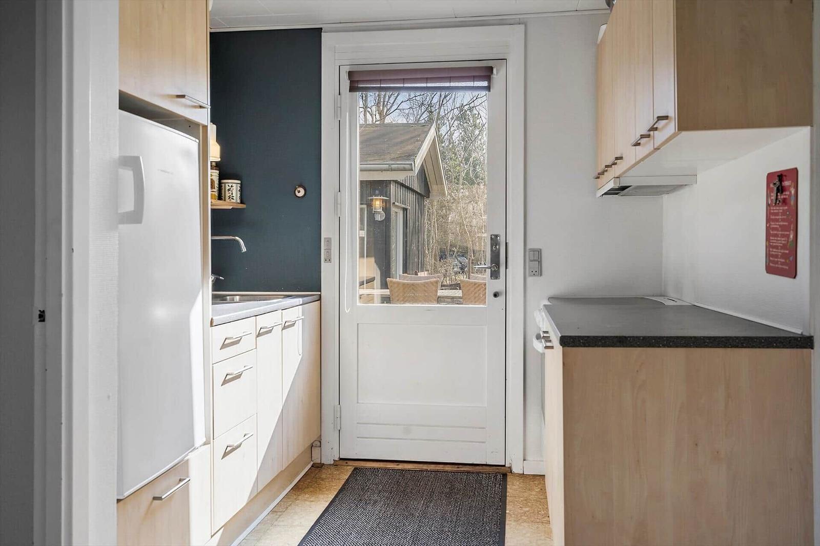 Kitchen with fridge, sink, and door to outdoor area.
