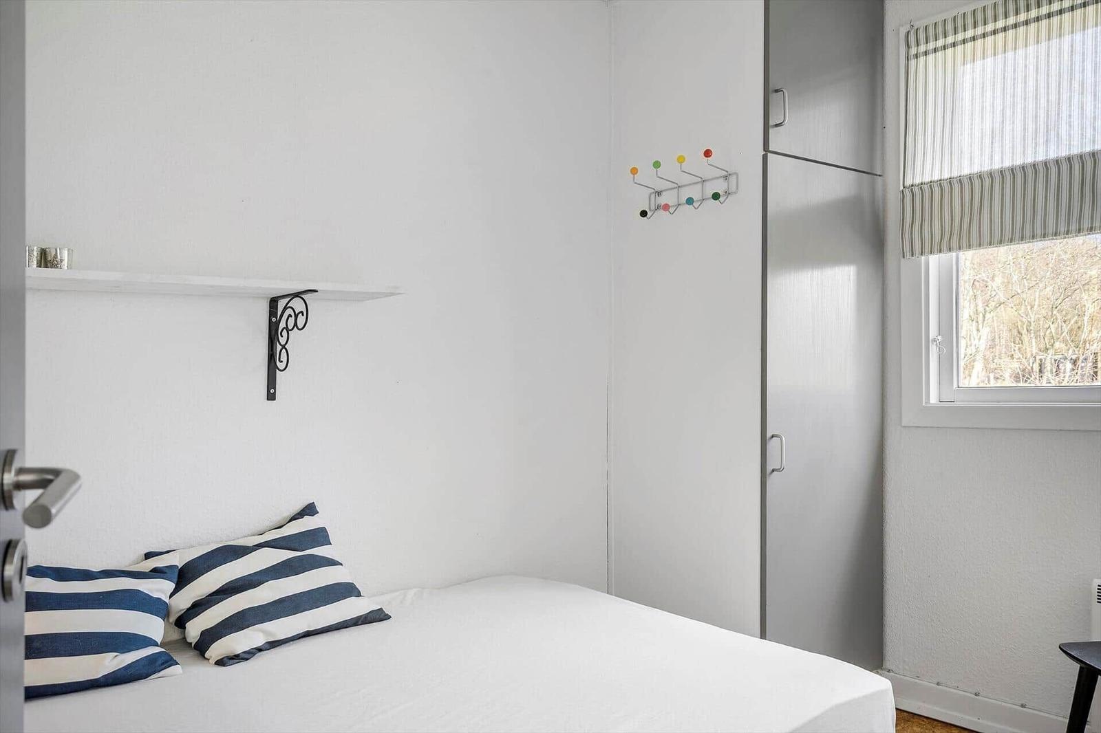 Bedroom with bed, coat hooks, and window.