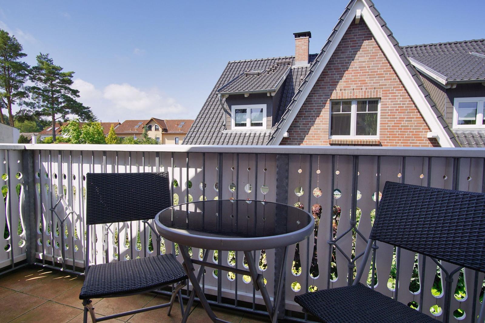 Terrasse mit Tisch und zwei Stühlen. Blick auf Haus mit Ziegelfassade.
