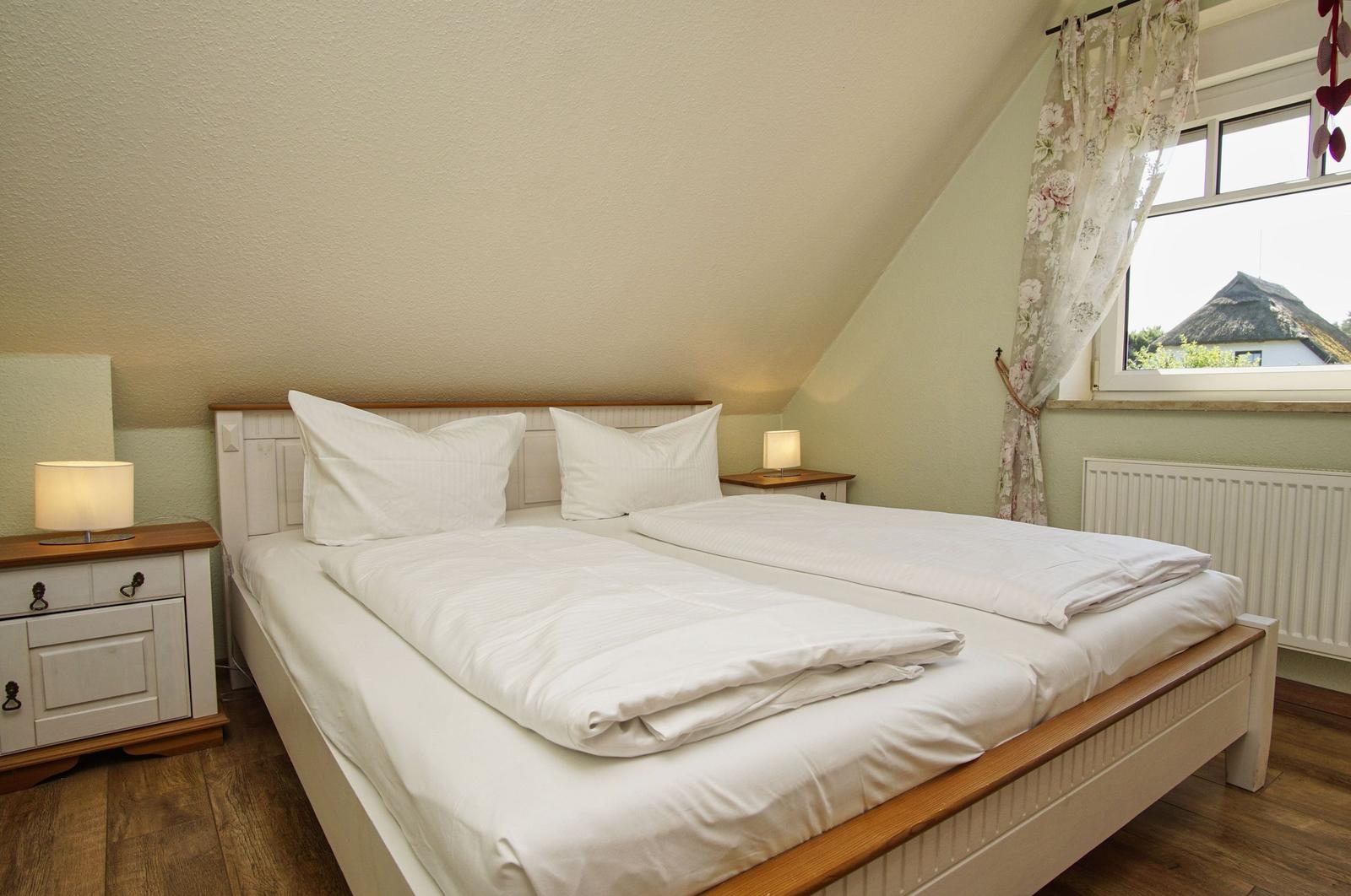 Schlafzimmer mit Doppelbett, Nachttischen und Fenster mit Blick.