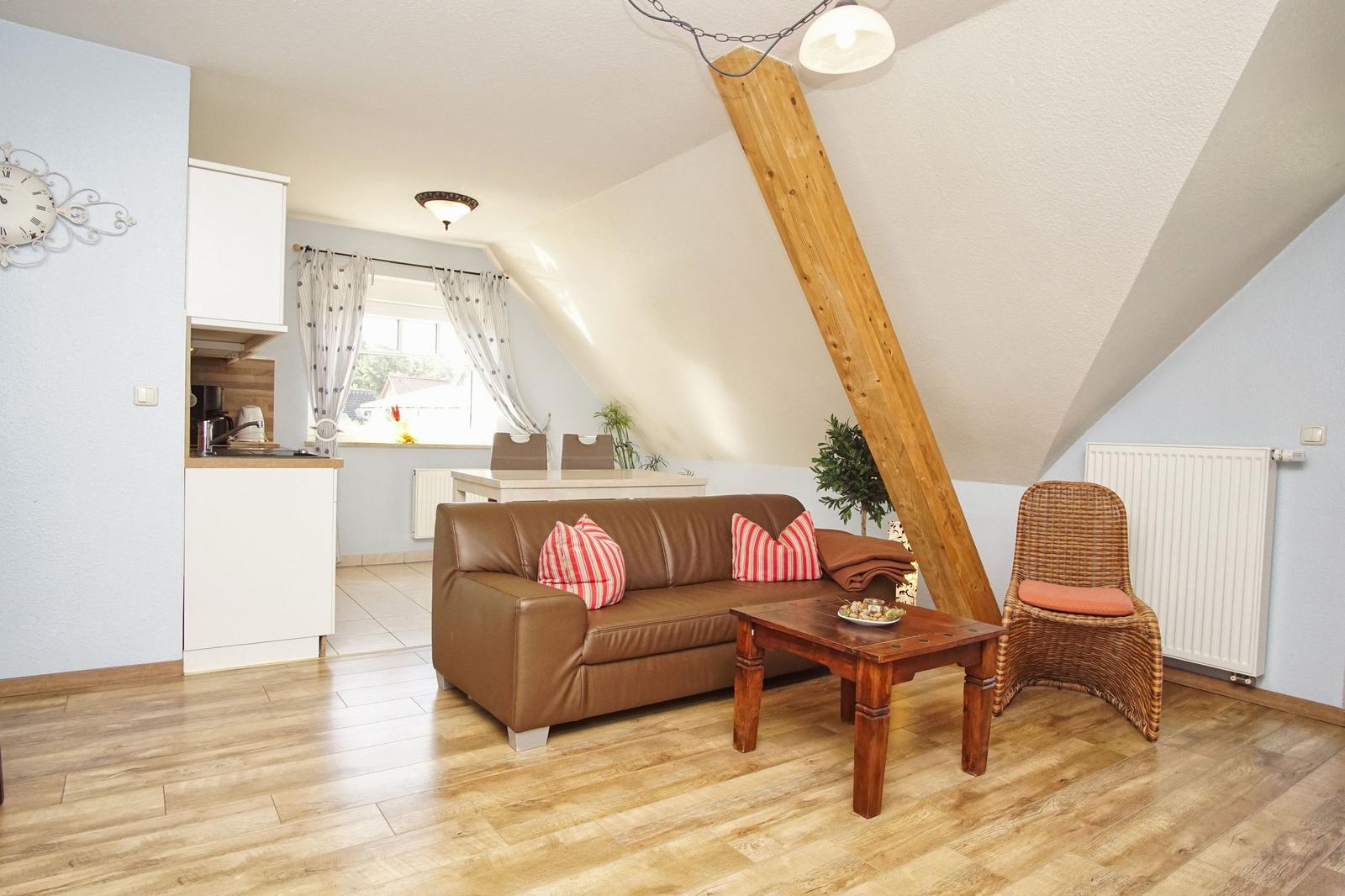 Wohnzimmer mit Sofa, Couchtisch und Sessel unter Dachschrägen.