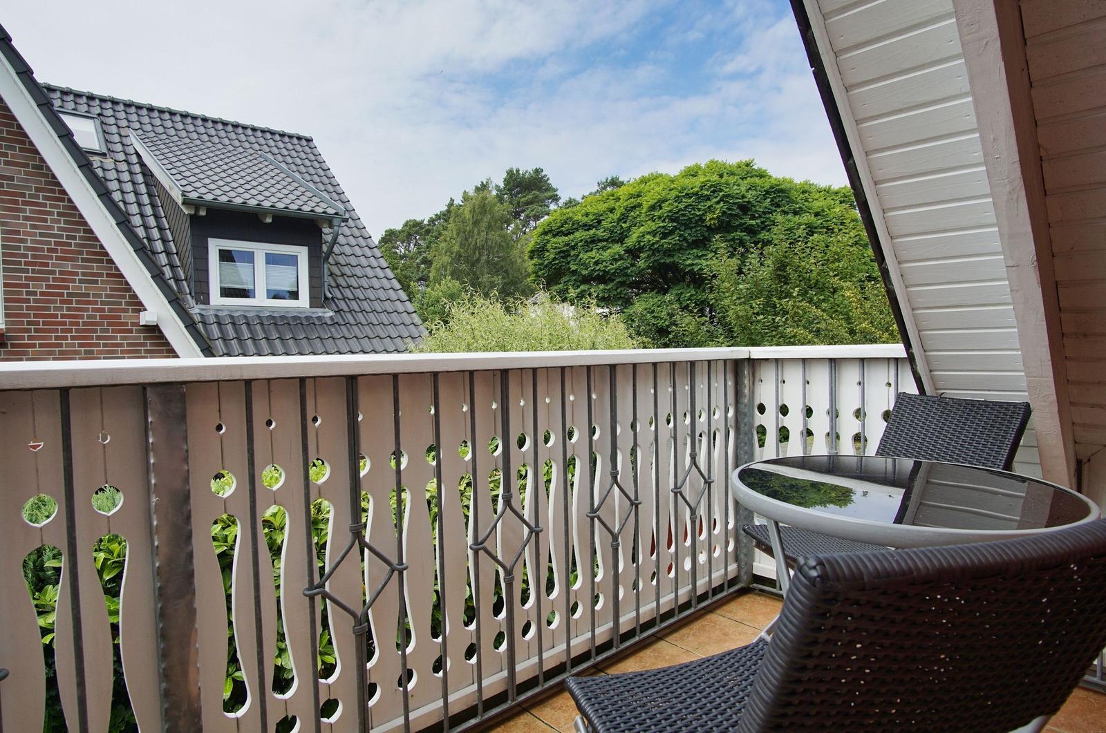 Terrasse mit Tisch und Stühlen, Blick auf Grün und Nachbarhaus.