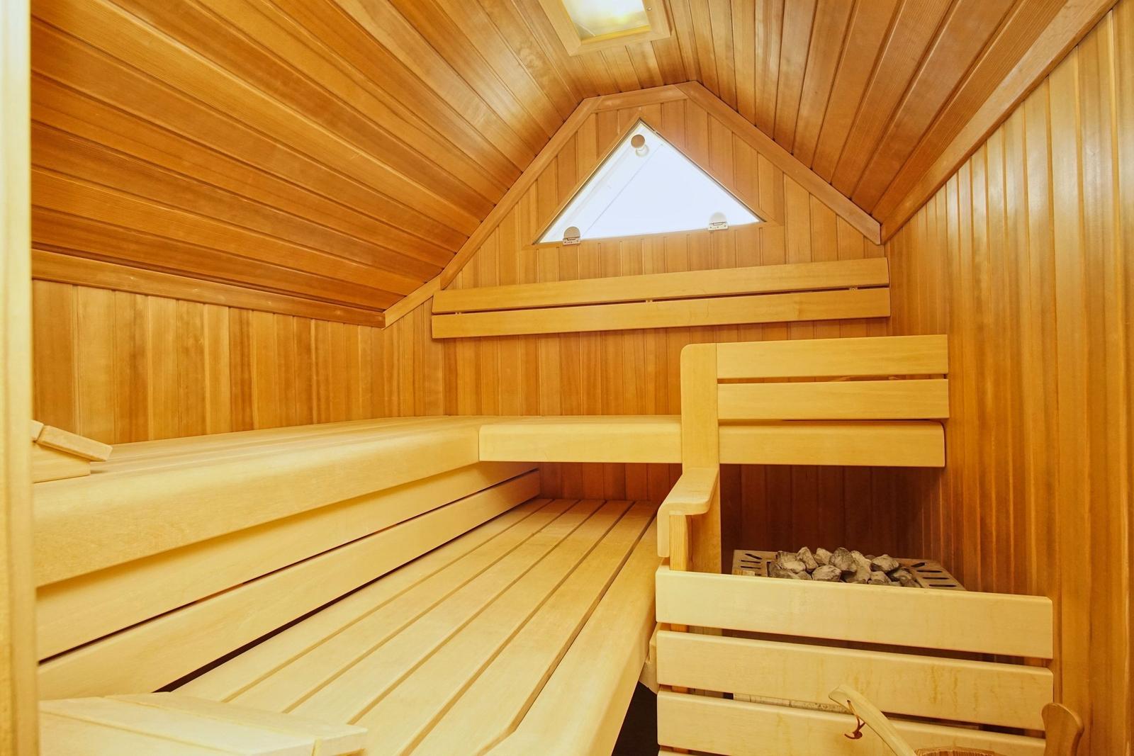 Holzsauna mit mehreren Bänken und einem Dachfenster.