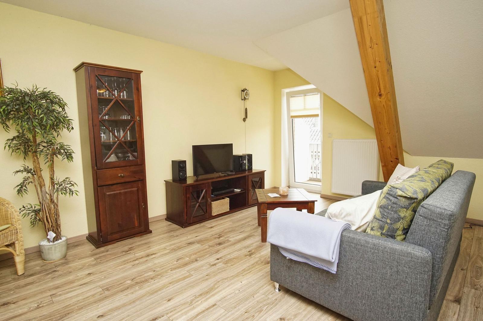 Wohnzimmer mit Sofa, Fernseher und Holzmöbeln.