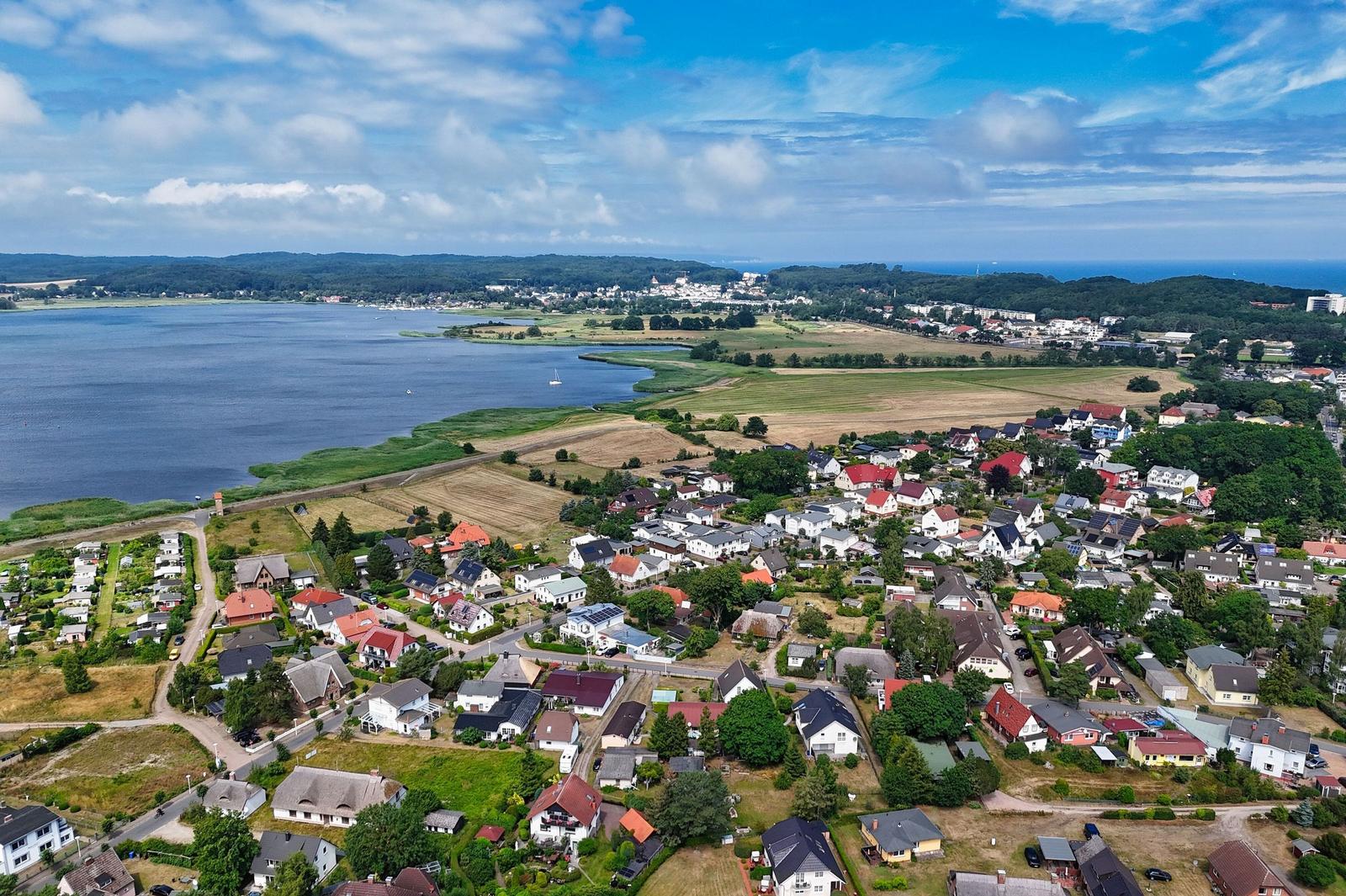 Aerial view of a coastal town with houses, fields, and a large water body.