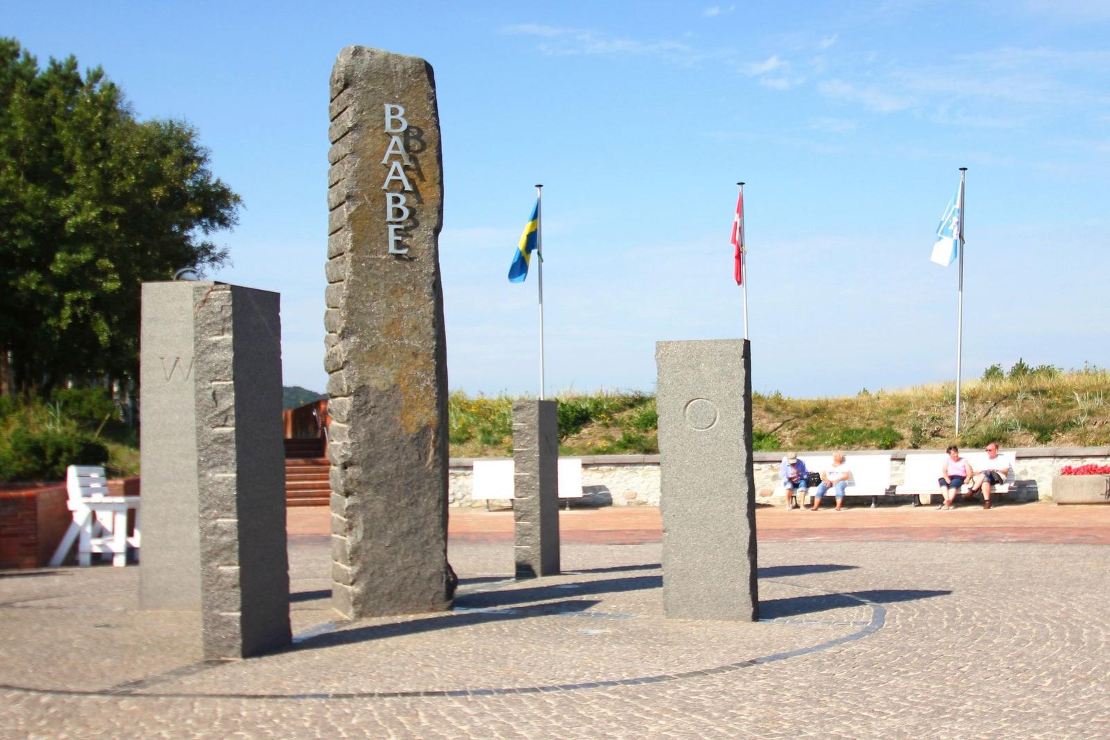 Stein-Skulptur mit Flaggen und Sitzgelegenheiten im Freien
