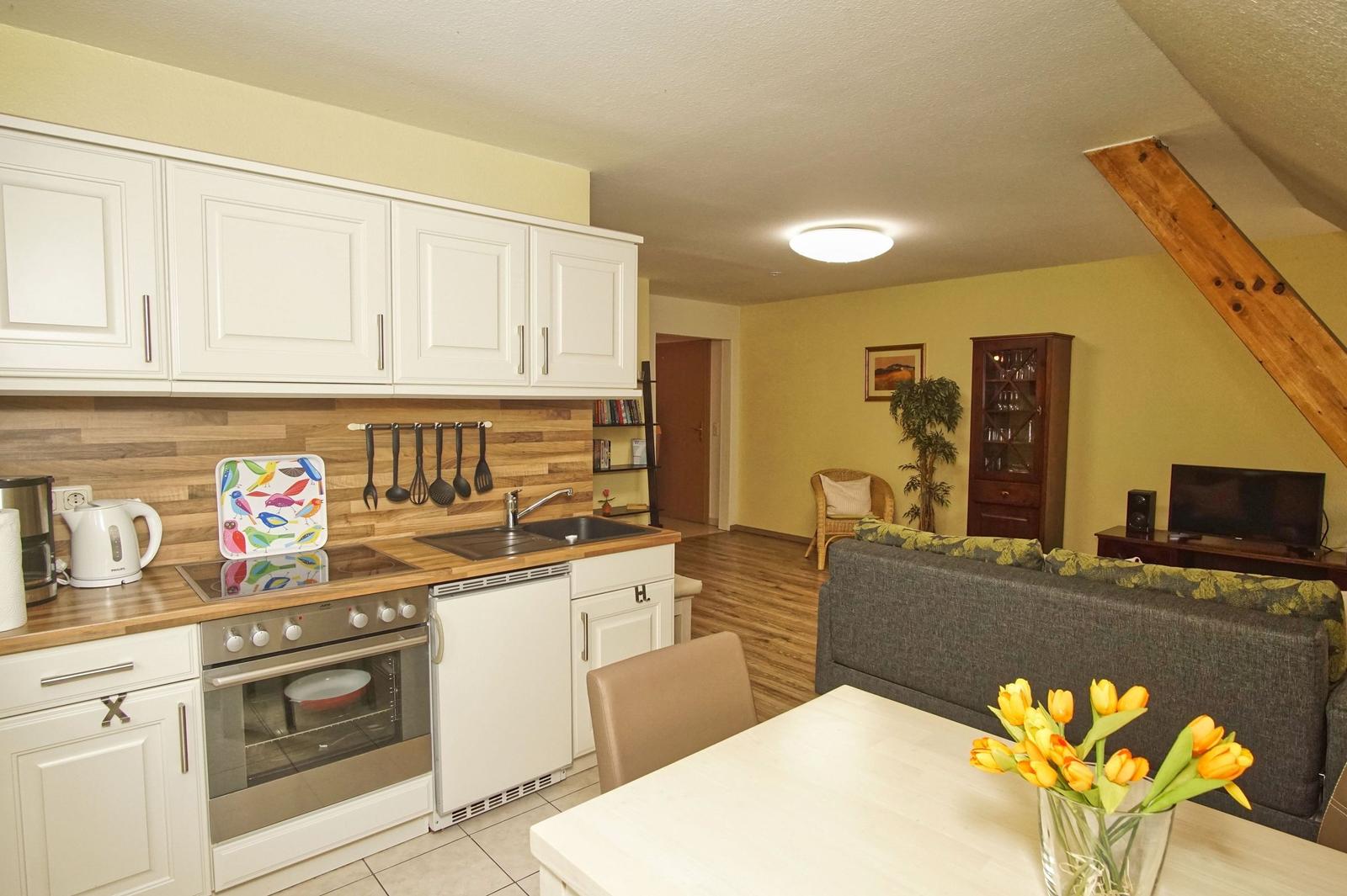 Küche mit Essbereich und Wohnzimmer mit Sofa und Fernseher.