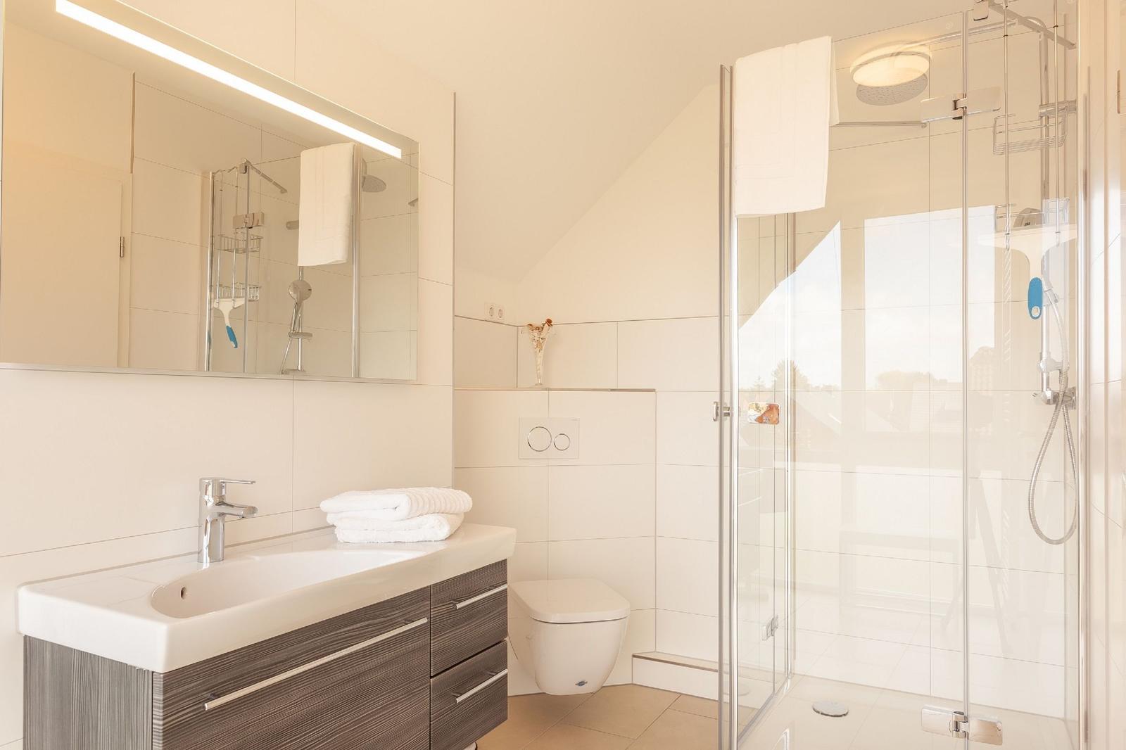 Badezimmer mit Dusche, Waschbecken und Toilette.