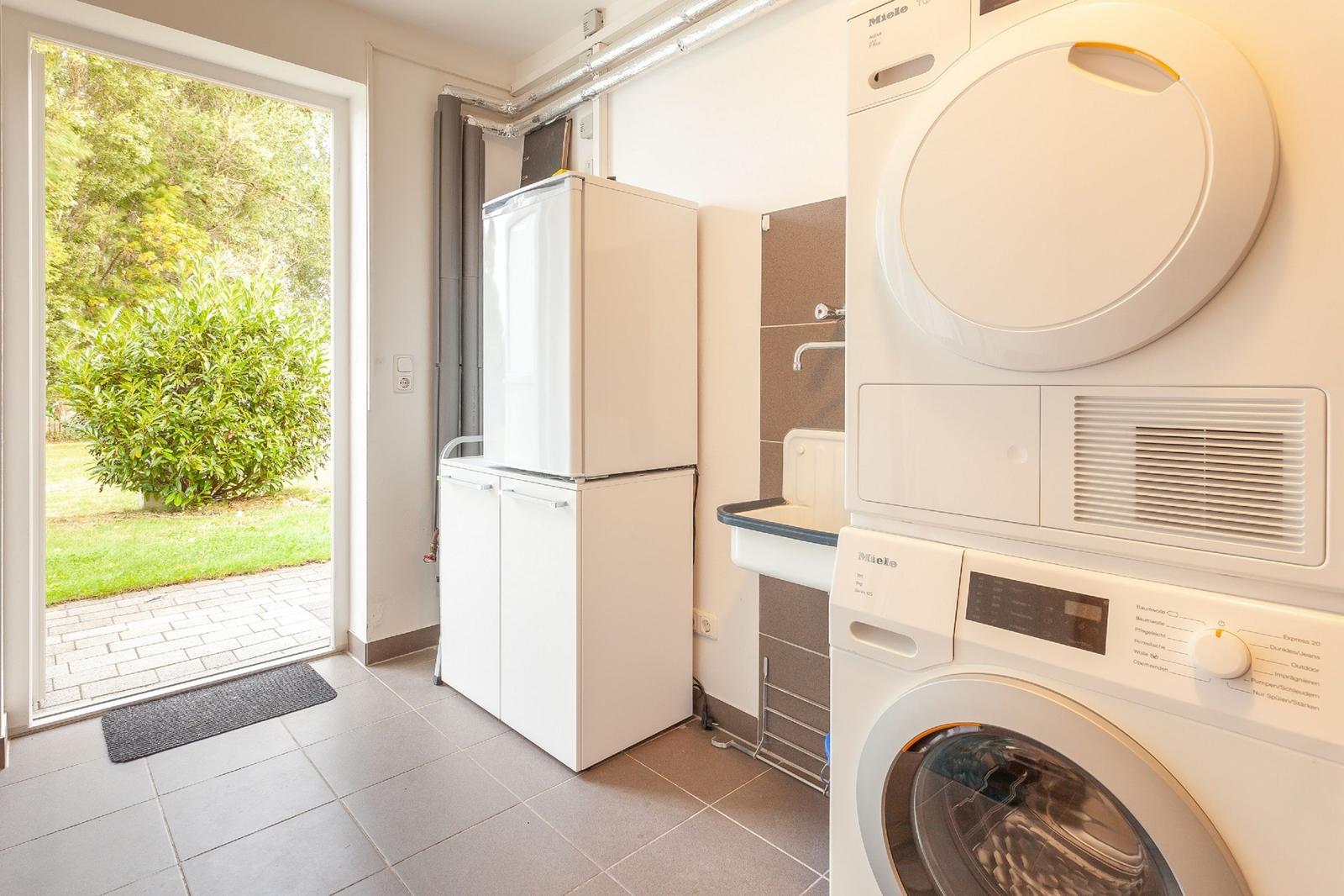 Wohnung mit Waschmaschine und Trockner, Kühlschrank und Blick auf Garten.