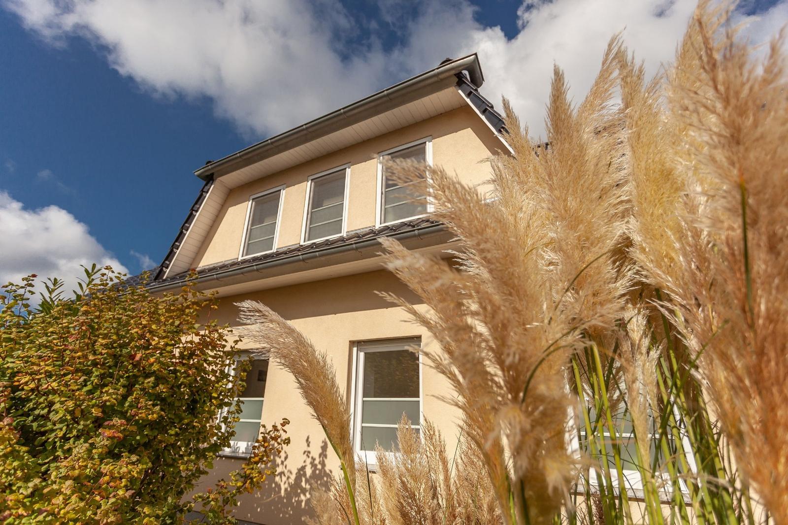 Ein zweistöckiges Haus mit Fenstern und Pflanzen im Vordergrund.