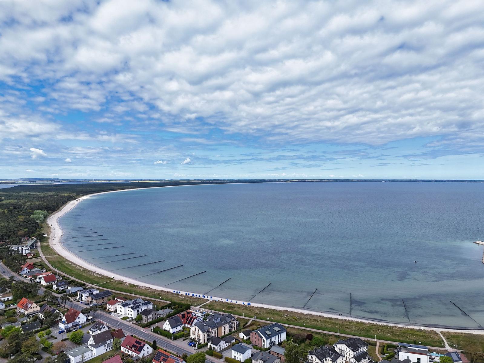 Aerielansicht eines Strandes mit Häusern und Meer unter bewölktem Himmel
