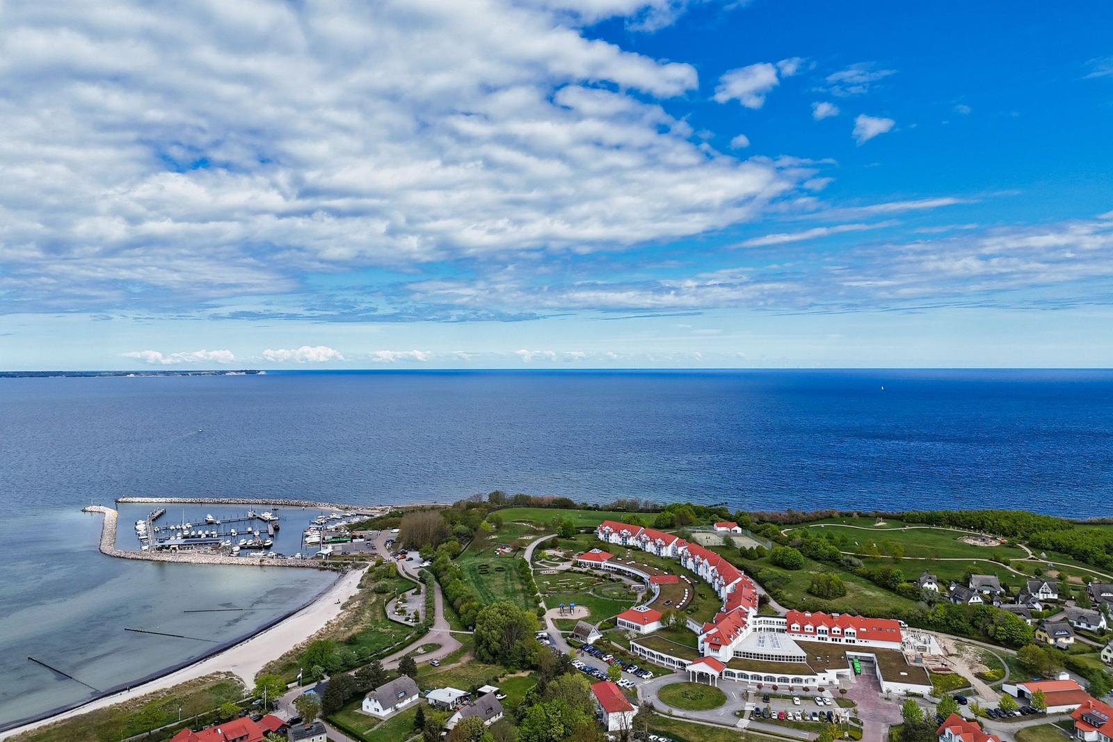 Hafen mit Booten, Strand und roten Dächern an der Küste.